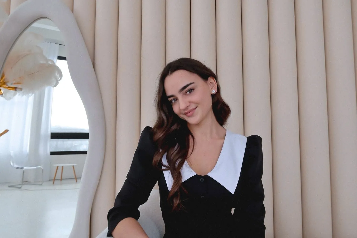 Аліна Михайлова усміхається на тлі бежевих панелей